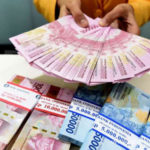 Seorang teller Bank Mandiri menunjukkan uang pecahan Rp100.000 dan Rp50.000 di Plasa Mandiri, Jakarta, Senin (8/7/2019).