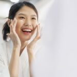 attractive-freshness-asian-woman-clean-face-fresh-water-with-care-look-mirror-bathroom-home-background (1)
